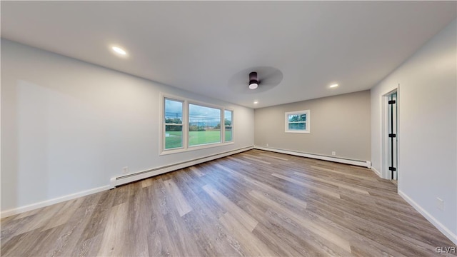 unfurnished room featuring a baseboard radiator and light hardwood / wood-style floors