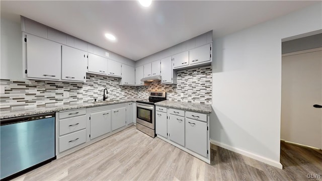 kitchen featuring stainless steel appliances, sink, light stone counters, and light wood-type flooring