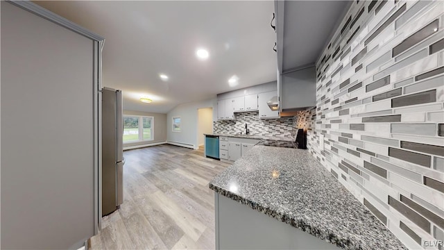 kitchen with dark stone countertops, gray cabinetry, decorative backsplash, stainless steel appliances, and light hardwood / wood-style flooring