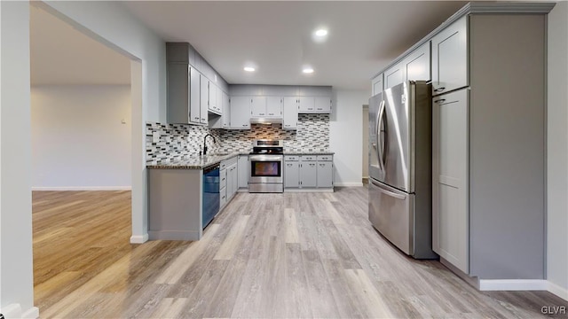 kitchen featuring sink, gray cabinets, appliances with stainless steel finishes, tasteful backsplash, and light hardwood / wood-style floors