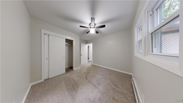 unfurnished bedroom featuring baseboard heating, ceiling fan, a closet, and carpet