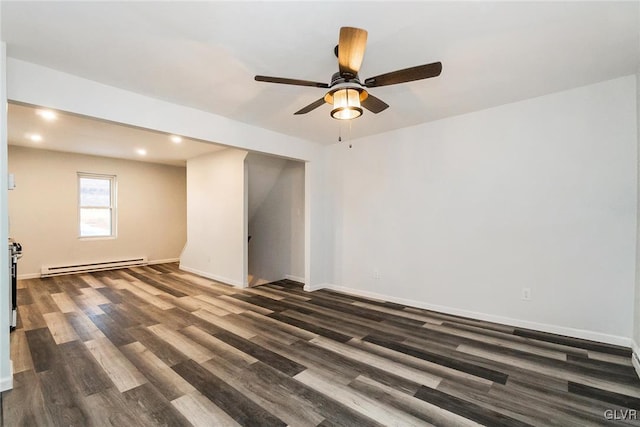 spare room featuring a baseboard heating unit and dark hardwood / wood-style flooring