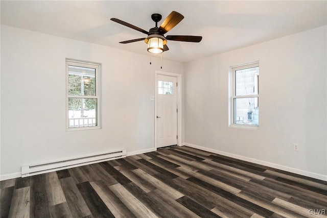 spare room featuring a baseboard radiator, a wealth of natural light, and dark hardwood / wood-style flooring