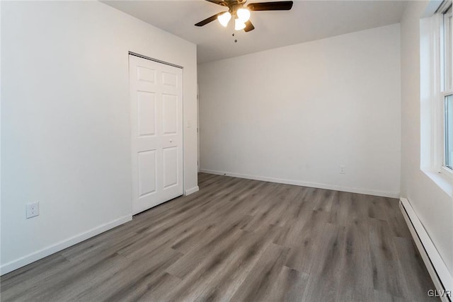 spare room featuring hardwood / wood-style flooring, ceiling fan, and baseboard heating