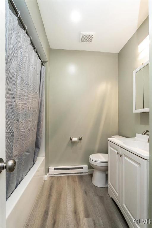 full bathroom with toilet, shower / tub combo, baseboard heating, vanity, and hardwood / wood-style flooring