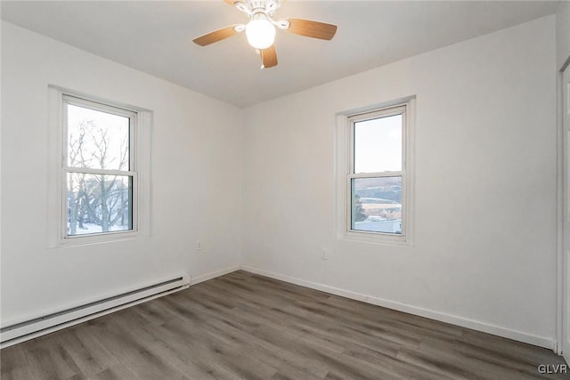 spare room with dark hardwood / wood-style flooring, a baseboard heating unit, a healthy amount of sunlight, and ceiling fan