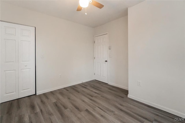 unfurnished bedroom featuring dark wood-type flooring, ceiling fan, and a closet