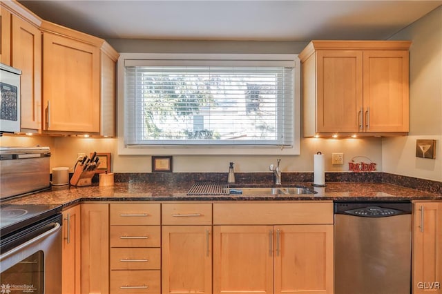 kitchen with appliances with stainless steel finishes, sink, light brown cabinetry, and dark stone counters