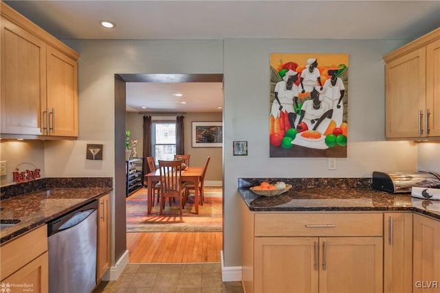 kitchen with dark stone countertops, dishwasher, and light brown cabinets