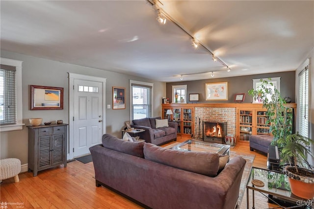 living room with a fireplace, light hardwood / wood-style floors, and rail lighting