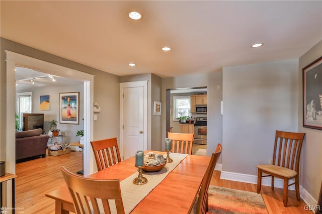 dining area featuring a fireplace, track lighting, and light wood-type flooring