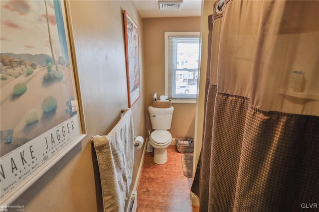 bathroom with wood-type flooring, a baseboard radiator, and toilet