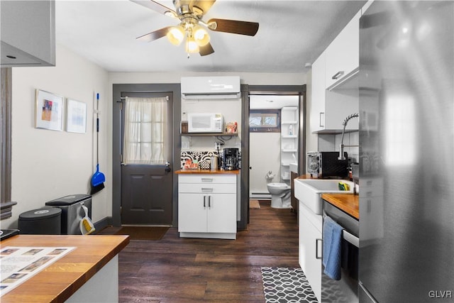 kitchen featuring wood counters, white cabinetry, an AC wall unit, and stainless steel refrigerator