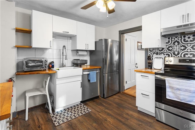 kitchen featuring white cabinetry, stainless steel appliances, butcher block countertops, and decorative backsplash