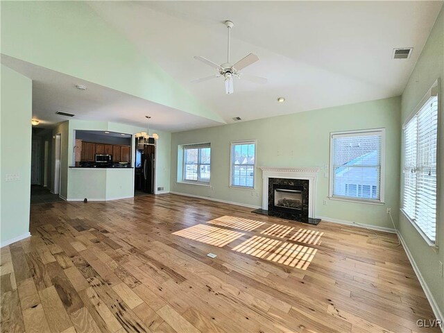 unfurnished living room with a high end fireplace, plenty of natural light, ceiling fan, and light wood-type flooring