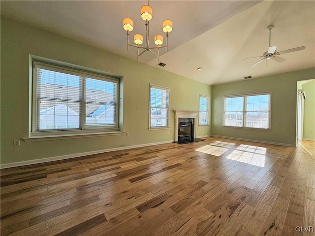 unfurnished living room featuring ceiling fan with notable chandelier, vaulted ceiling, and wood-type flooring