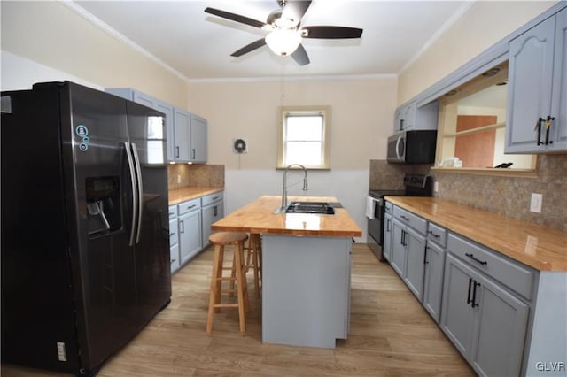 kitchen with butcher block counters, sink, a breakfast bar area, appliances with stainless steel finishes, and backsplash