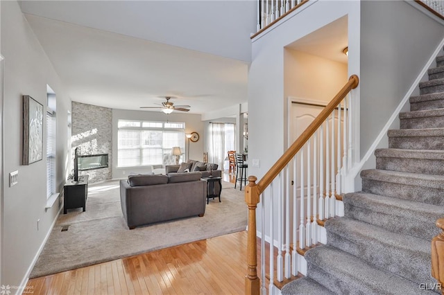 living room featuring a fireplace, wood-type flooring, and ceiling fan