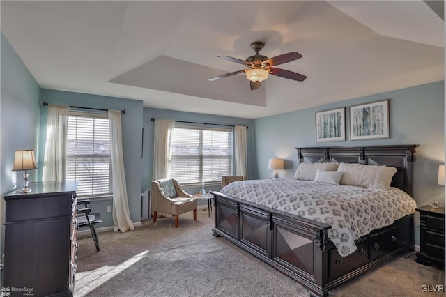 carpeted bedroom with ceiling fan and a tray ceiling