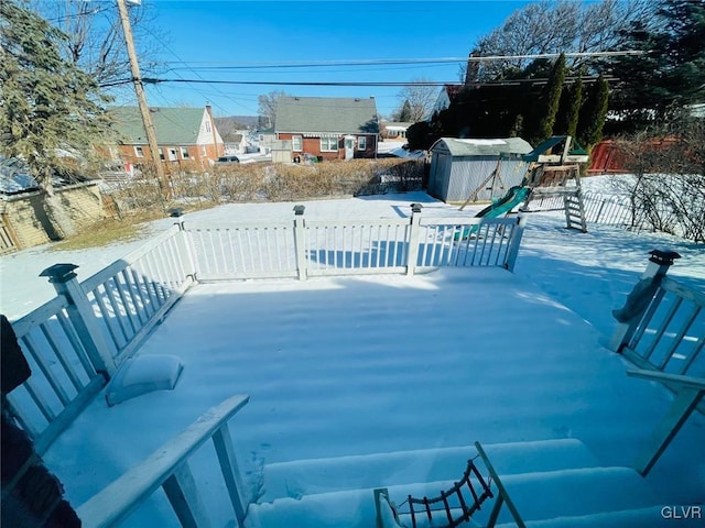 snow covered patio featuring a storage shed