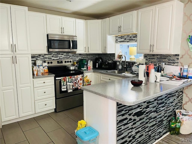 kitchen featuring appliances with stainless steel finishes, sink, white cabinets, and kitchen peninsula