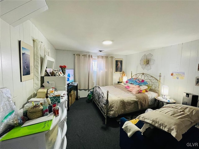 bedroom with carpet and wood walls