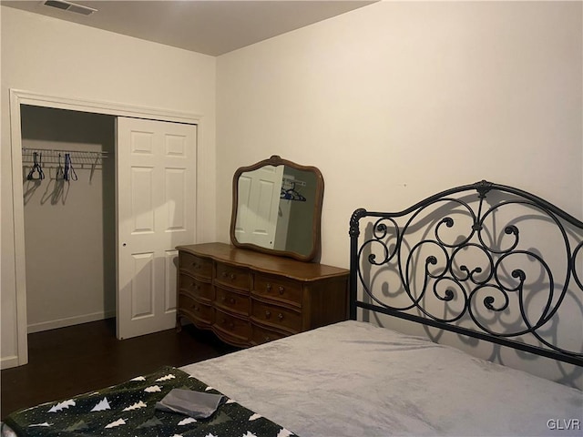 bedroom with dark wood-type flooring and a closet