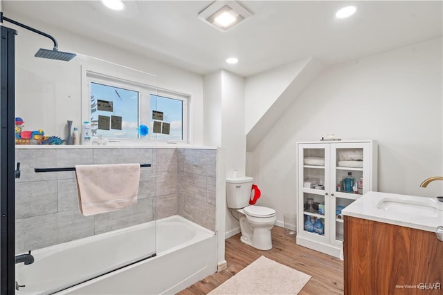 full bathroom with tiled shower / bath, vanity, toilet, and hardwood / wood-style floors