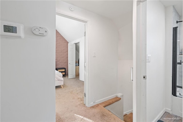 corridor with vaulted ceiling and light carpet