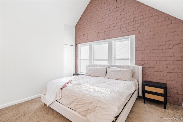 carpeted bedroom featuring vaulted ceiling and brick wall