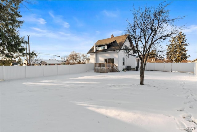 snow covered back of property featuring central AC unit