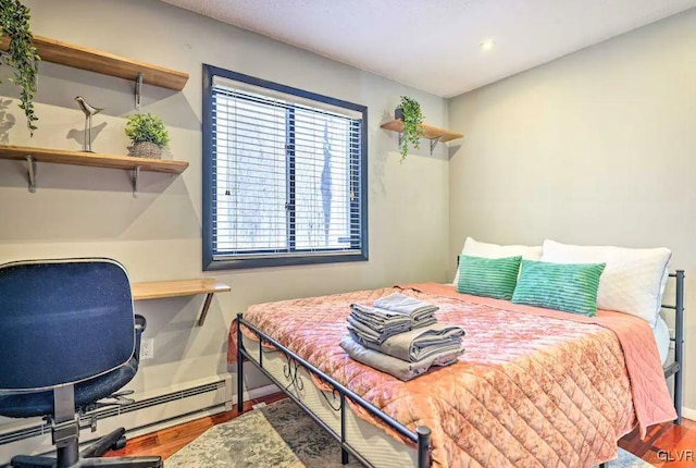 bedroom with baseboard heating and wood-type flooring