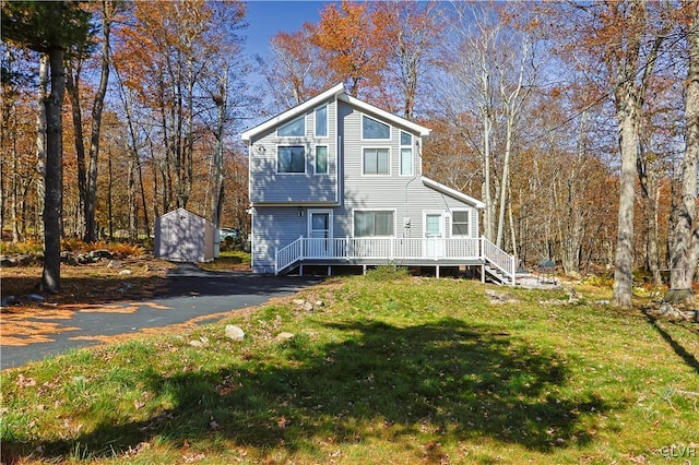 view of front of home with a wooden deck, a front lawn, and a shed