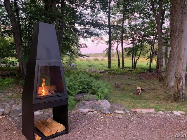 yard at dusk featuring an outdoor fireplace