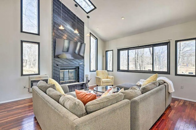 living room with dark hardwood / wood-style flooring, lofted ceiling, heating unit, and a fireplace