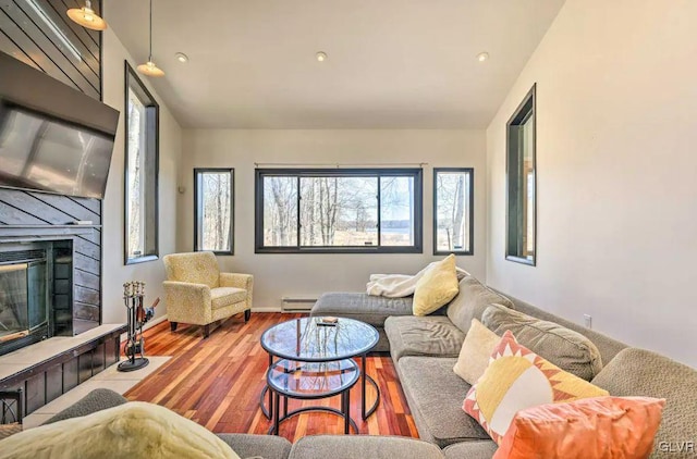 living room featuring hardwood / wood-style flooring, a tile fireplace, and baseboard heating