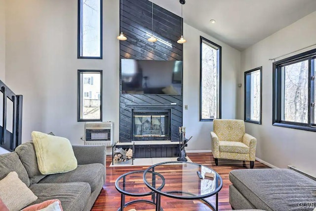 living room with a large fireplace, plenty of natural light, hardwood / wood-style floors, and heating unit