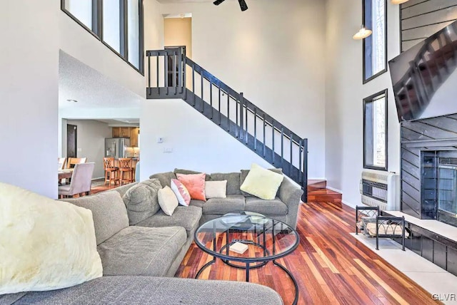 living room featuring heating unit, wood-type flooring, and a high ceiling