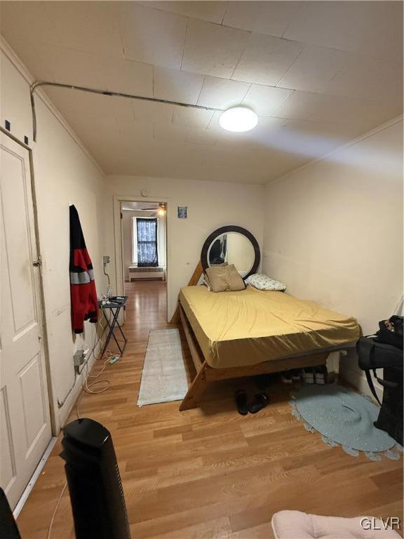 bedroom with ornamental molding and hardwood / wood-style floors