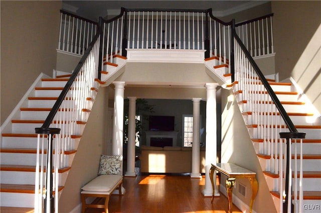 staircase with hardwood / wood-style floors and ornate columns