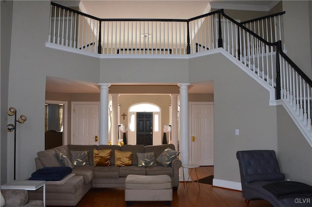 living room featuring hardwood / wood-style flooring, a towering ceiling, and decorative columns