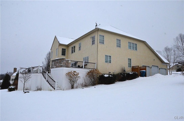 snow covered house featuring a garage