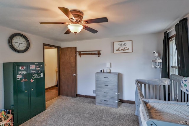 bedroom with a nursery area, light colored carpet, and ceiling fan