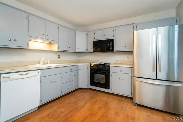 kitchen with sink, gray cabinetry, light hardwood / wood-style floors, and black appliances