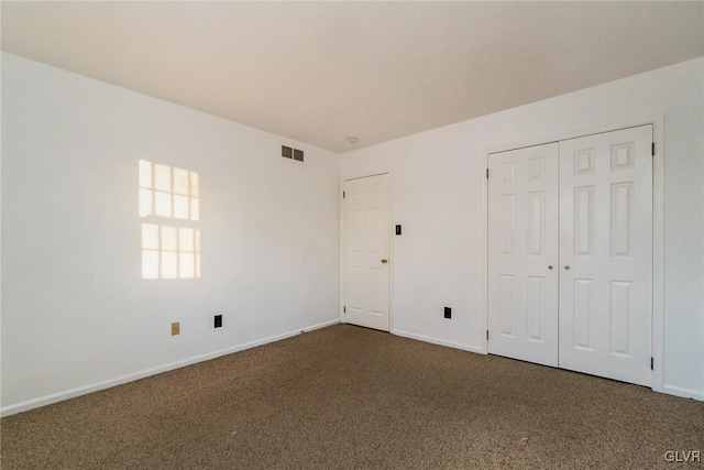 unfurnished bedroom with dark carpet and a closet