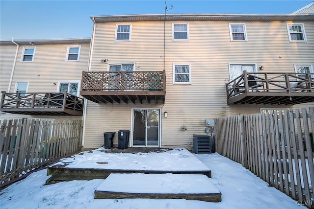 snow covered property with central AC and a deck