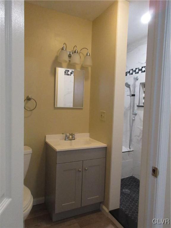 bathroom with vanity, tiled shower, and toilet