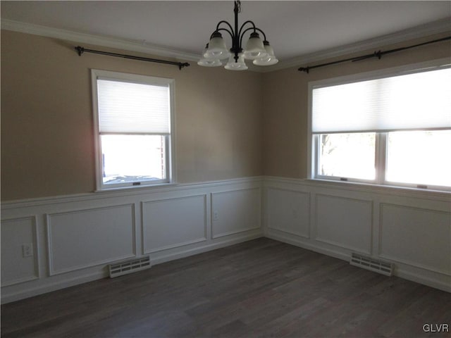 empty room featuring a notable chandelier, crown molding, plenty of natural light, and dark hardwood / wood-style floors