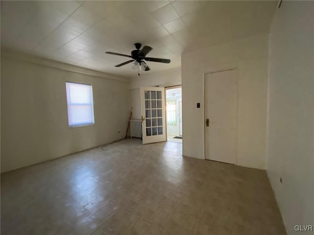 unfurnished room with radiator heating unit, ceiling fan, and french doors