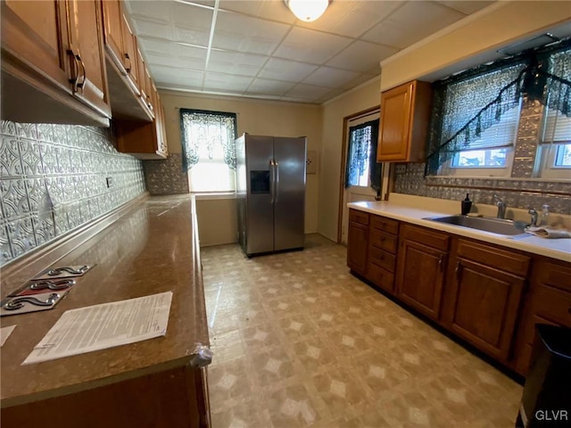 kitchen featuring a drop ceiling, stainless steel fridge with ice dispenser, decorative backsplash, and sink